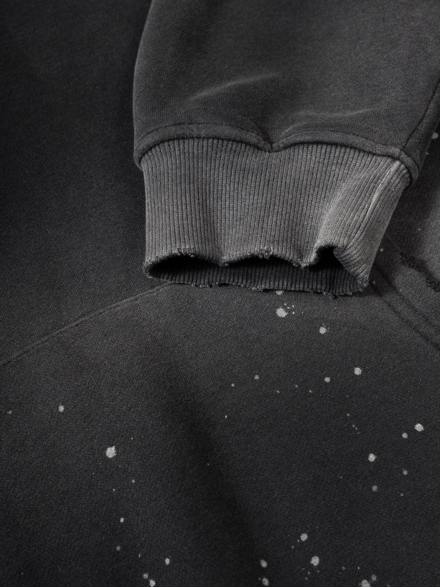 Close-up of a dark gray hoodie with frayed edges on a matching background