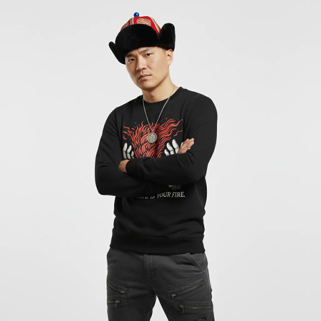 Person wearing a black sweatshirt with red and white design and a black hat with colorful details on a light gray background