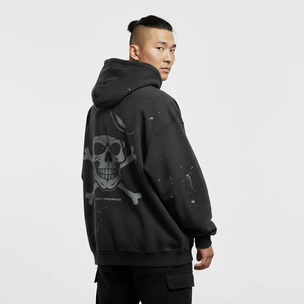 Person wearing a black hoodie with a skull design on the back against a light gray background