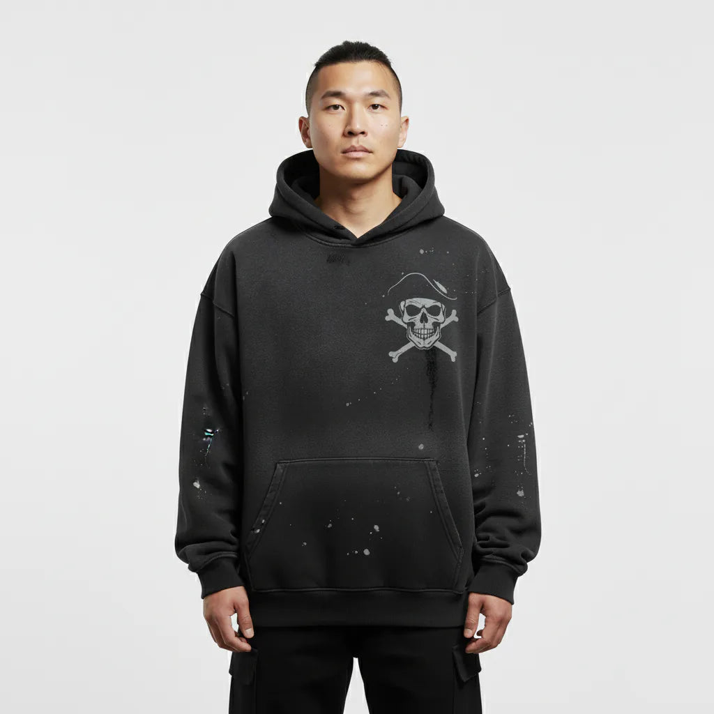 Person wearing a black hoodie with a skull and crossbones design on a white background