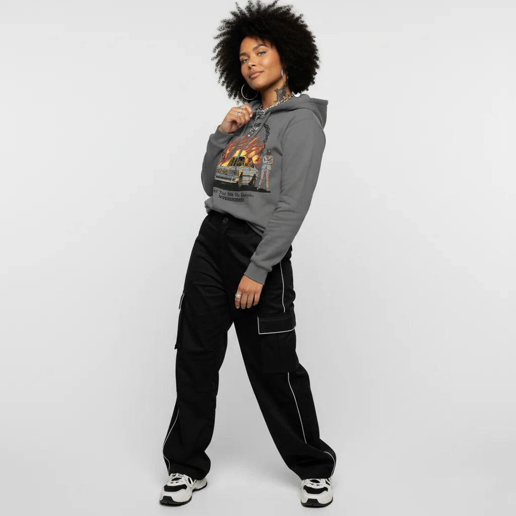 Person wearing a gray hoodie with a graphic design and black pants on a white background
