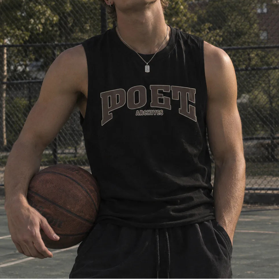 A young man standing on an outdoor basketball court holding a basketball, wearing a black sleeveless POET brand jersey with gray lettering.