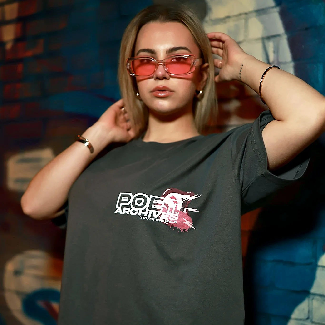 Person wearing a dark t-shirt with a logo in front of a colorful mural.