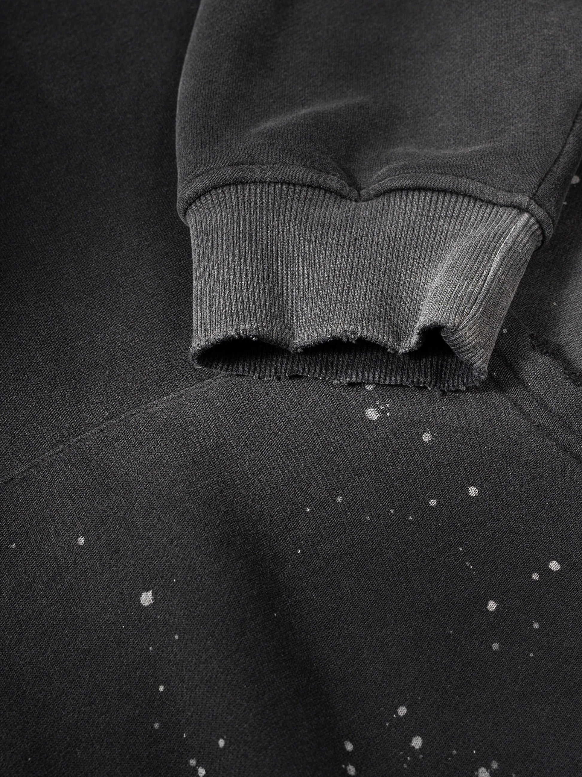 Close-up of a dark gray hoodie with frayed edges on a matching background