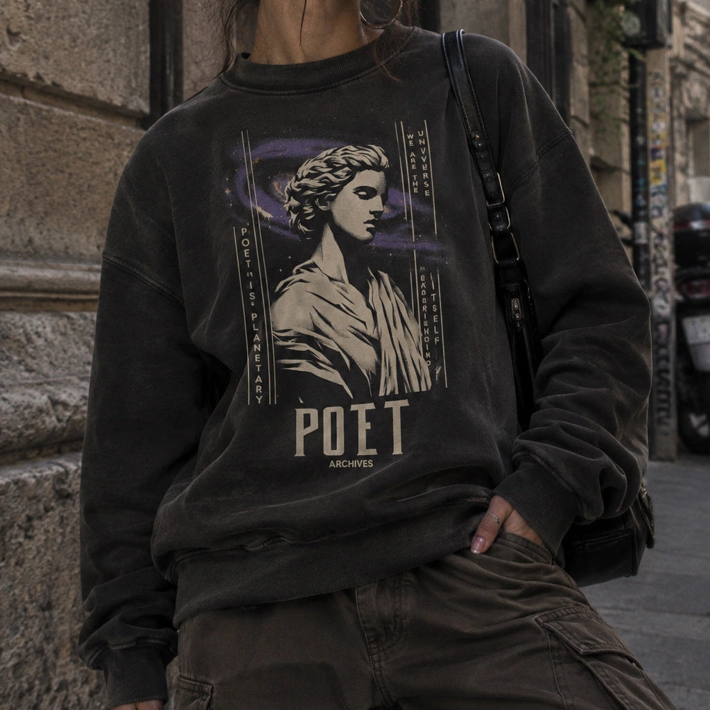 A woman wearing a dark charcoal gray graphic sweatshirt with a classical statue print and the word 'POET ARCHIVES' on the front, paired with olive cargo pants, standing in an outdoor urban alleyway.