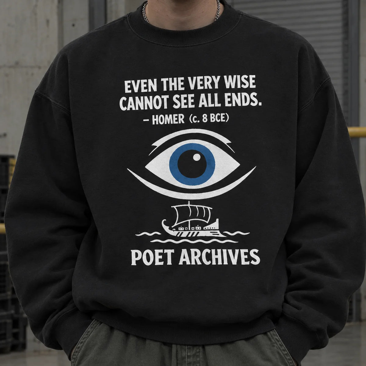 A person wearing a black crewneck sweatshirt with a white graphic print featuring a quote by Homer, a stylized eye with a blue iris, a small ship, and the text 'POET ARCHIVES'.