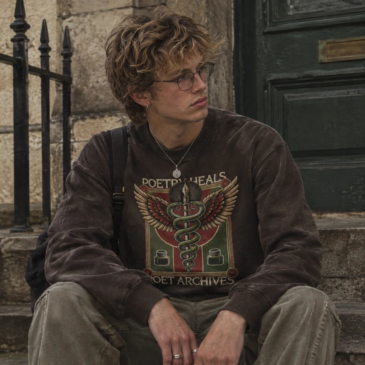Close-up of the winged snake staff graphic printed on a dark brown sweatshirt, from Poet Archives