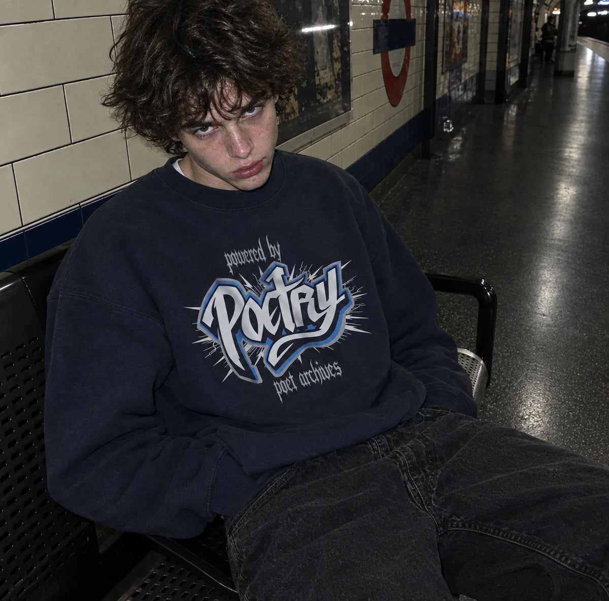 Person wearing a navy 'Powered by Poetry' sweatshirt with an electric graphic design, from Poet Archives