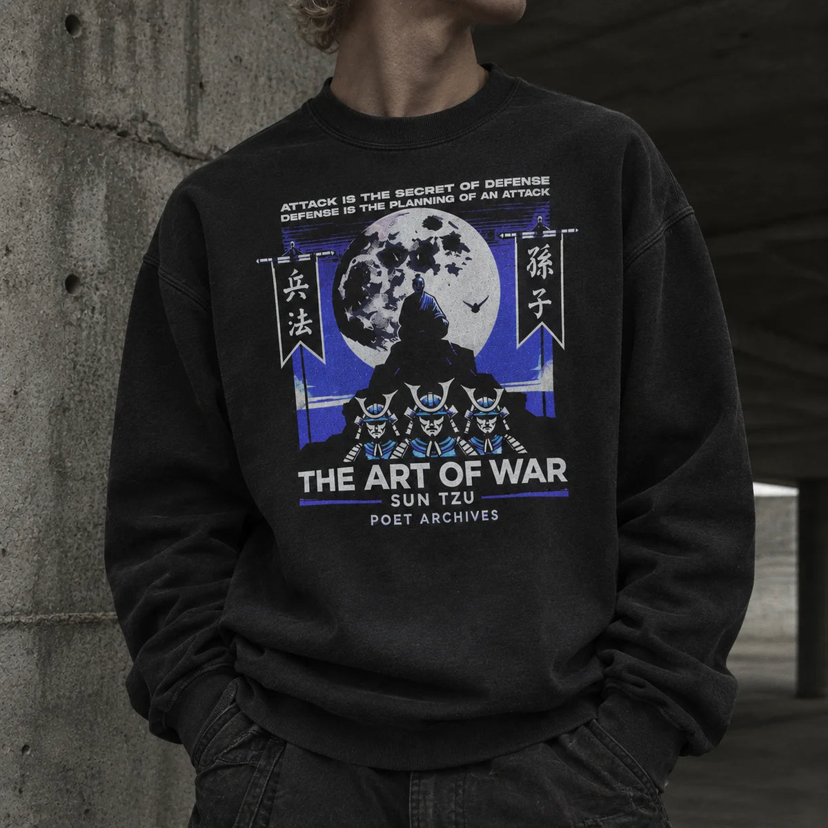 A person wearing a black crewneck sweatshirt with a detailed graphic print on the front. The graphic features a moon, Japanese characters, and the text 'THE ART OF WAR SUN TZU POET ARCHIVES'.