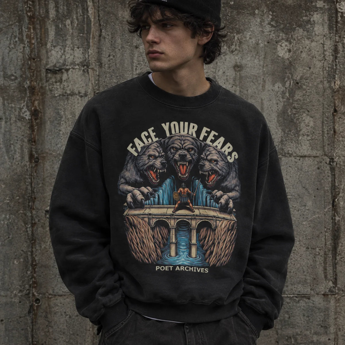 A man wearing a black graphic sweatshirt with a detailed illustration of three roaring wolves and the text 'FACE YOUR FEARS' and 'POET ARCHIVES', standing against a textured concrete wall.