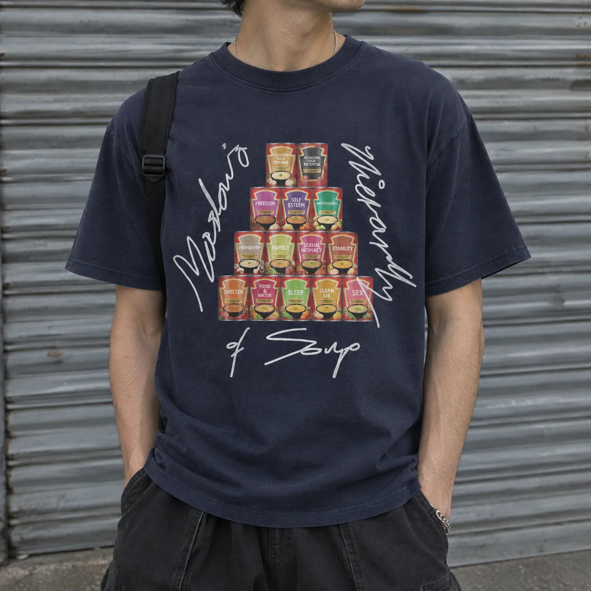A person wearing a navy blue graphic t-shirt with a pyramid of colorful soup cans and white script text reading 'Mick Jorgensen of Soup'.
