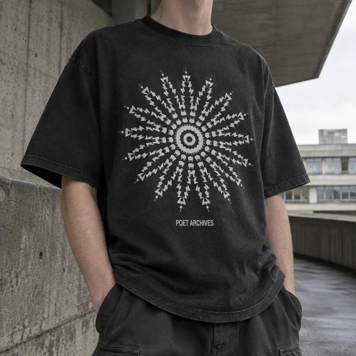 A person wearing a faded black graphic t-shirt with a white circular starburst design and the text 'POET ARCHIVES' printed below it, set against an outdoor concrete structure background.