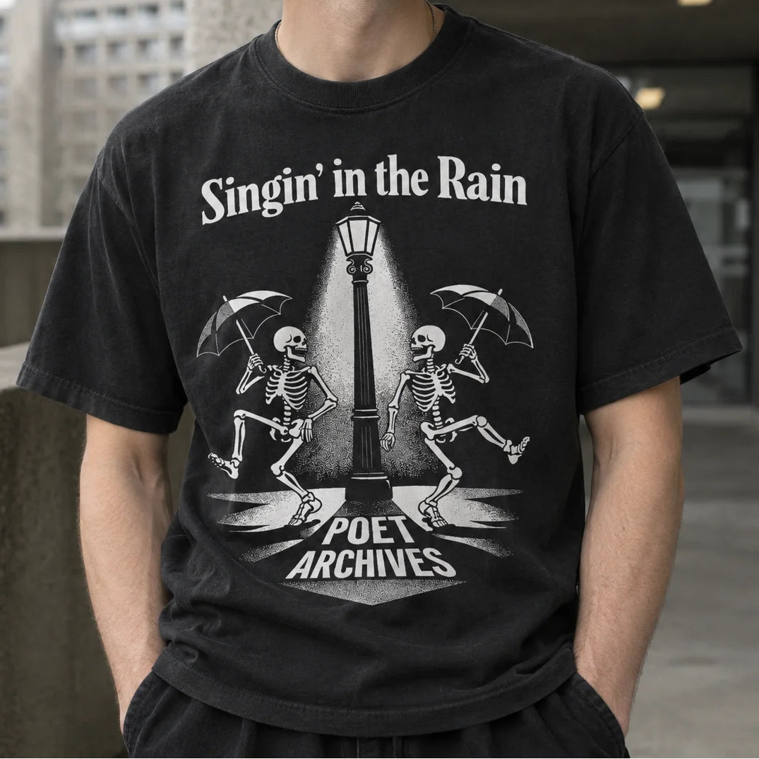A man wearing a black graphic t-shirt with a white print of two dancing skeletons under a streetlamp and the text 'Singin' in the Rain' and 'Poet Archives'.