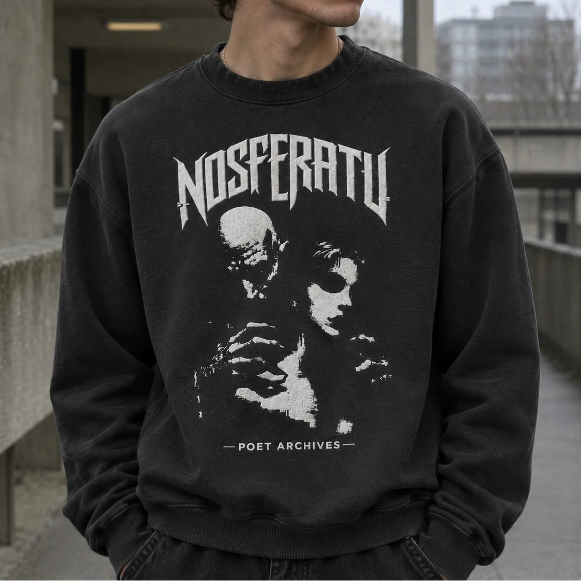 A person wearing a dark charcoal crewneck sweatshirt with a distressed white graphic print of the band Nosferatu and the text 'POET ARCHIVES'. The background is an outdoor concrete walkway.