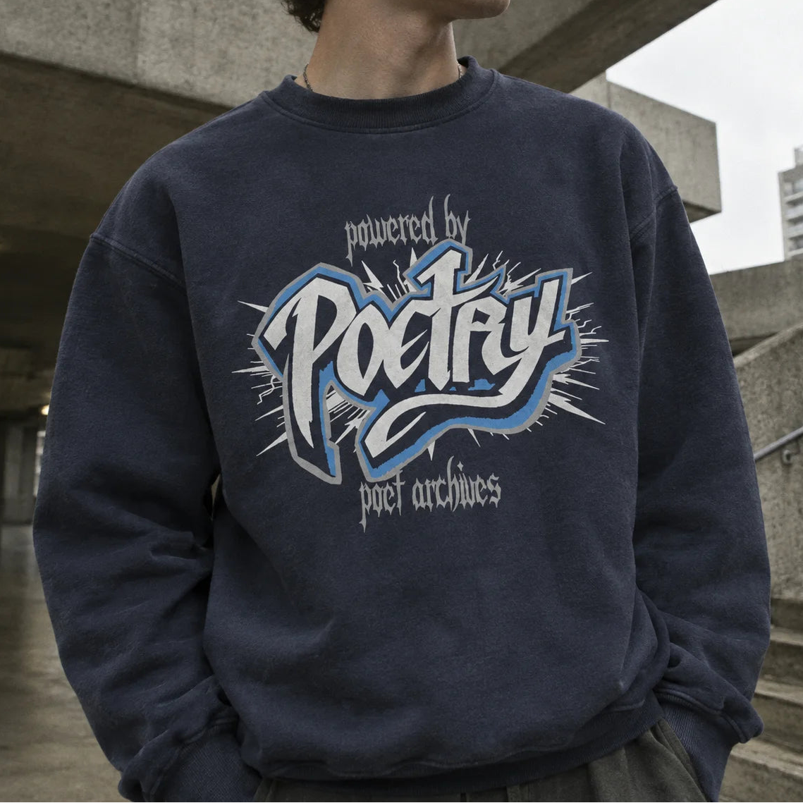 A man wearing a navy blue crewneck sweatshirt with a large graphic on the front that reads 'powered by Poctry poet archives' in white and light blue, set against an urban concrete background.